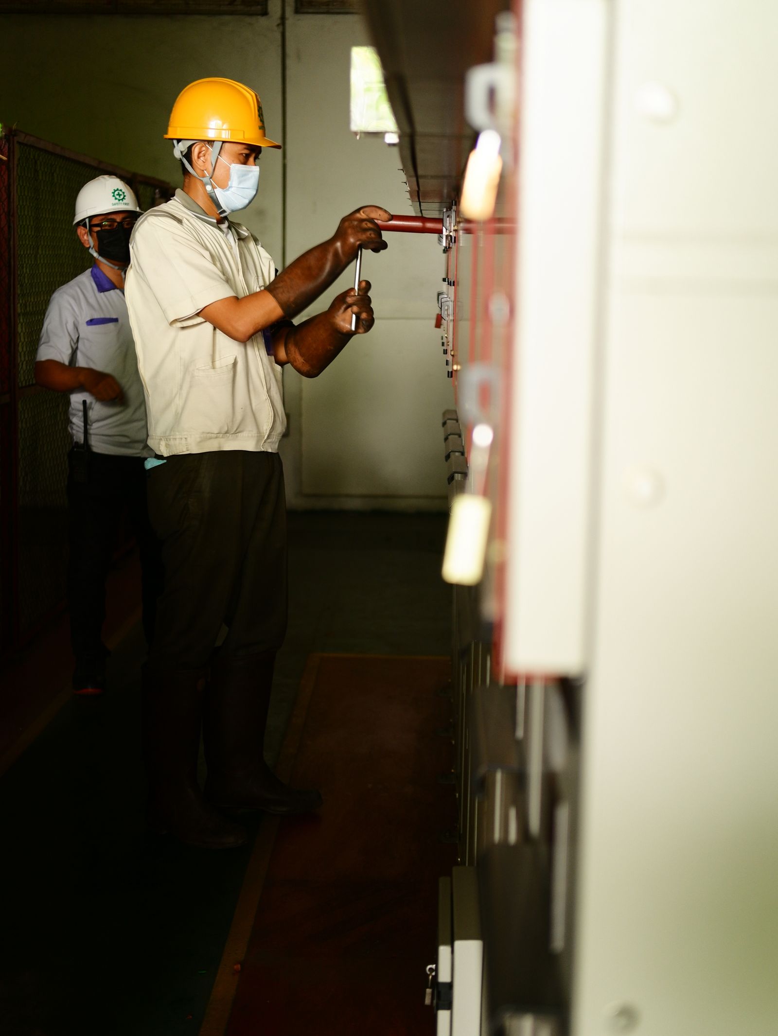 Electricians in hard hats servicing switchgear panels