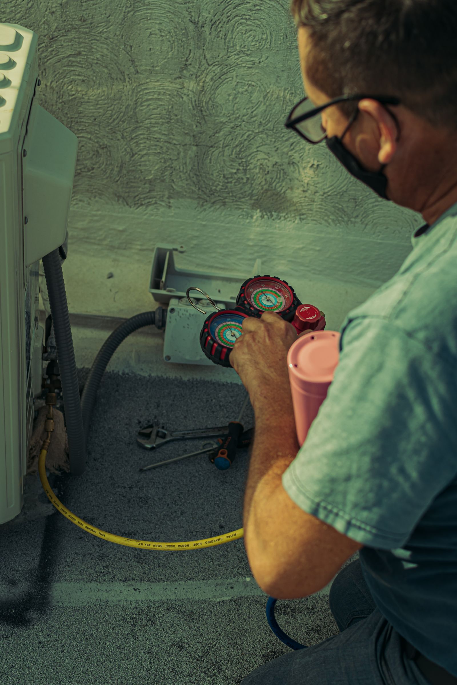 Technician checking air-conditioning refrigerant pressure with gauges