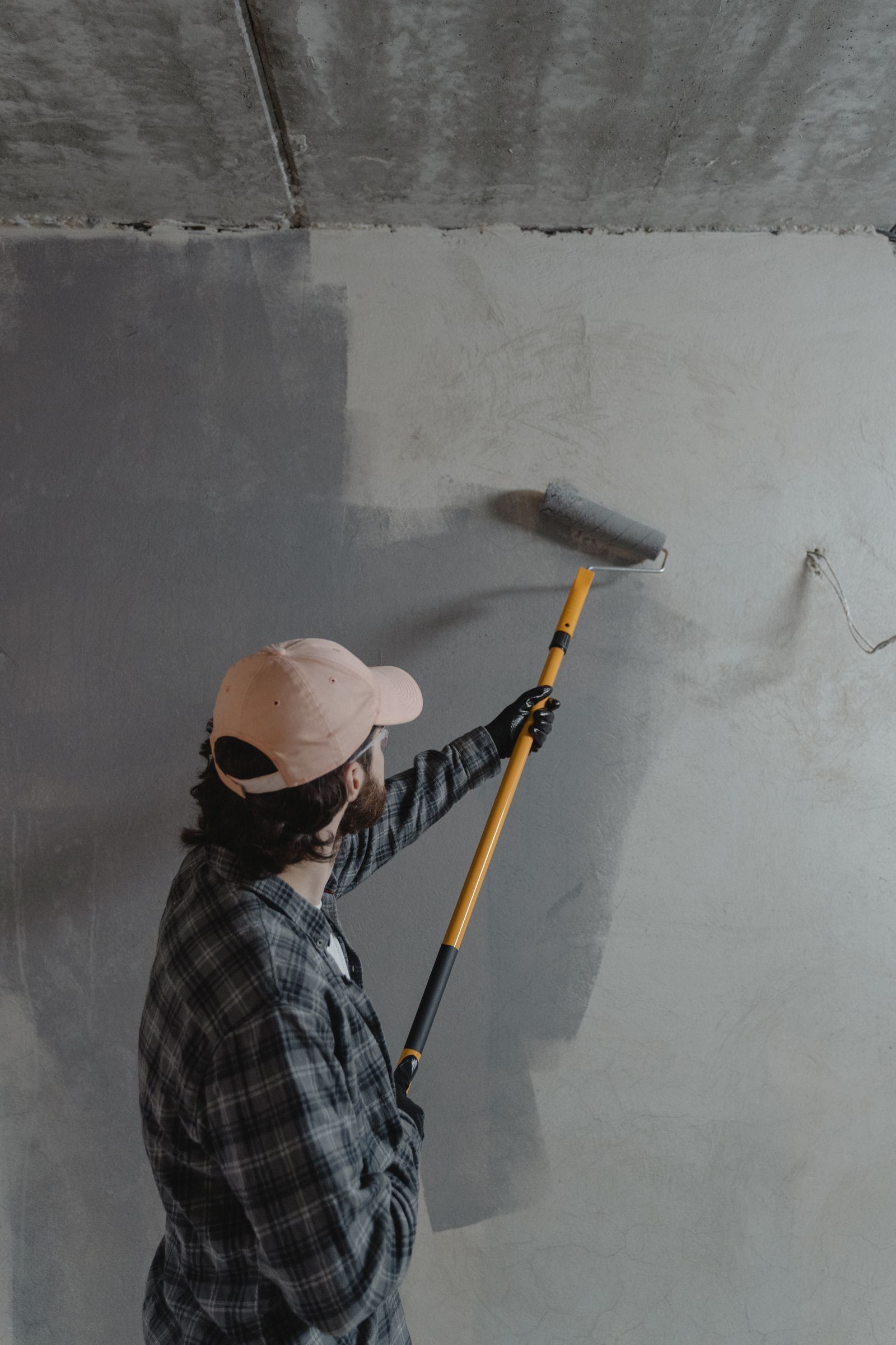 Painter applying grey paint to a wall with a roller