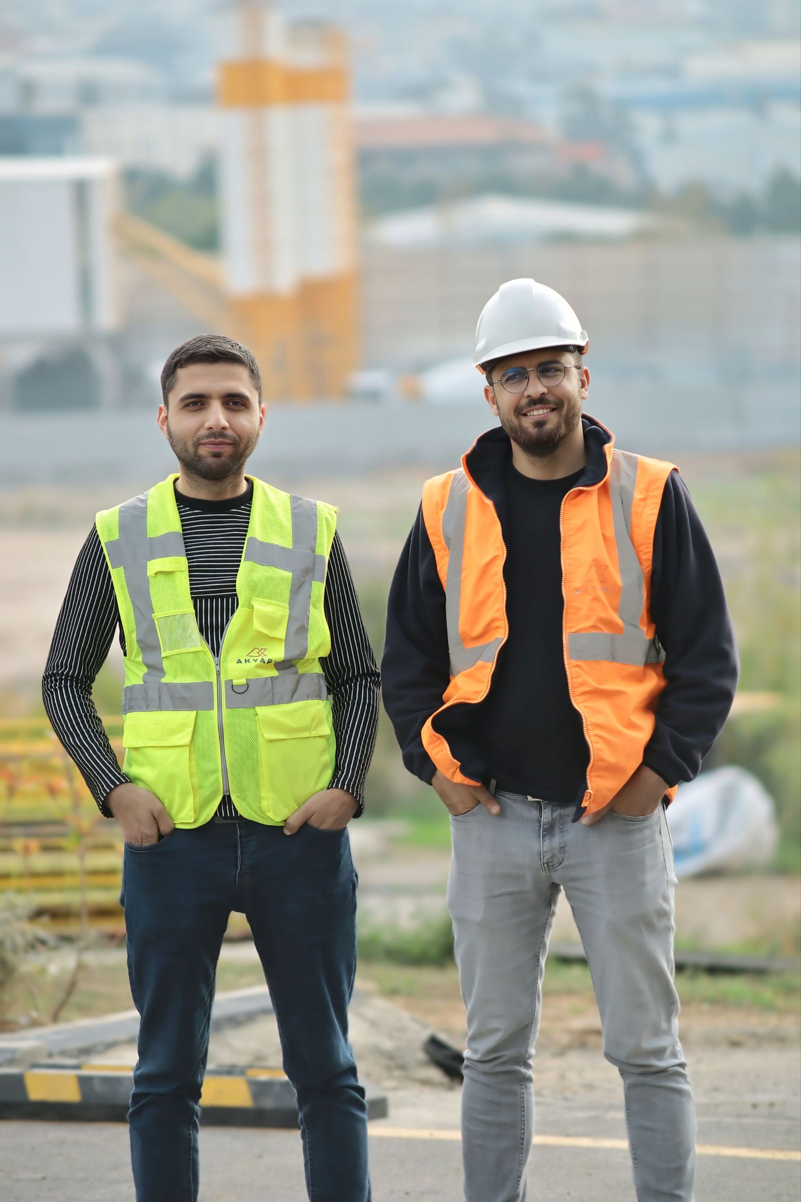 Two site supervisors in high-visibility vests and a hard hat on a project site